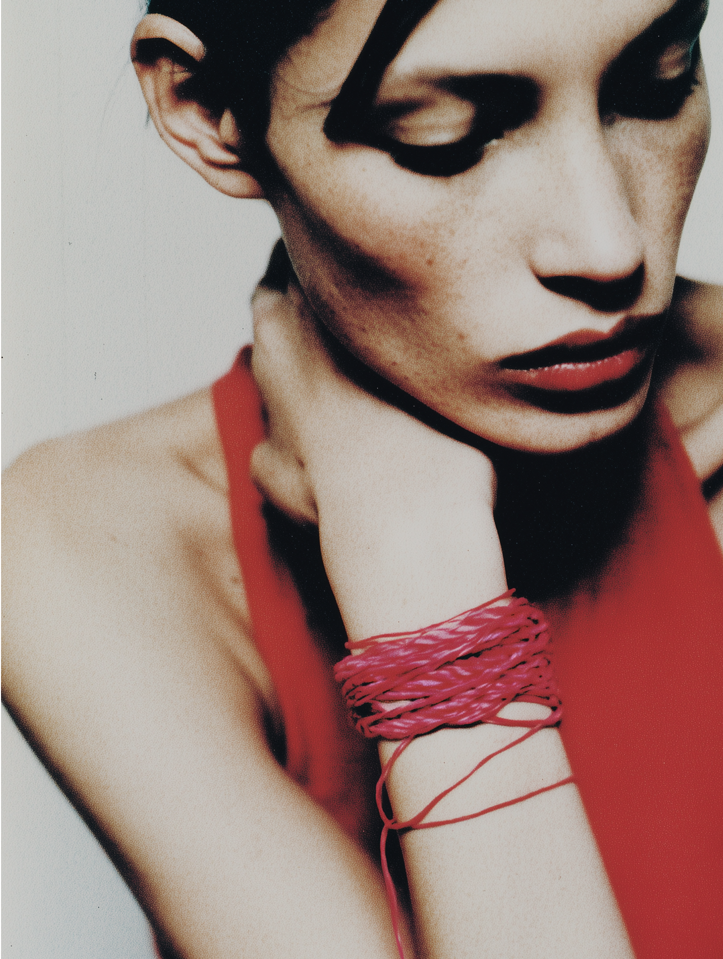 Woman with red halter top and bound arm against a plain background